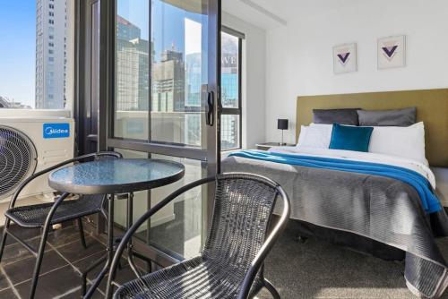 1 dormitorio con 1 cama, mesa y sillas en Gorgeous Cityscape Apartment in Auckland's CBD, en Auckland