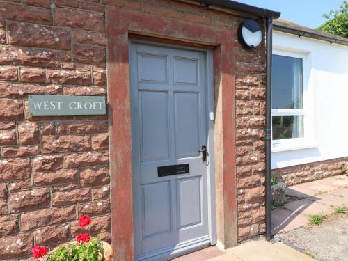 a door to the west croft cottage with a brick wall at West Croft in Mawbray