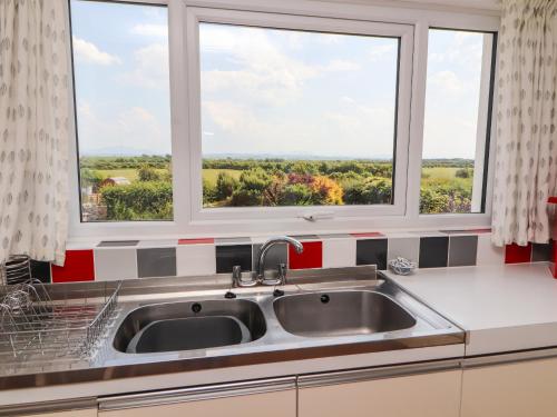 a kitchen with a sink and two windows at West Croft in Mawbray