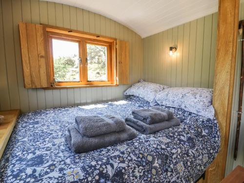 a bedroom with a bed with towels on it at Llethr - Shepherds Hut in Llanbedr