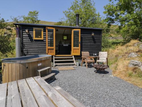 a log cabin with a hot tub and a patio at Llethr - Shepherds Hut in Llanbedr