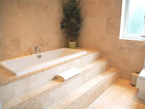 a bathroom with a tub and a potted plant at Willow Brook in Glossop