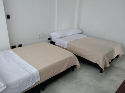 2 Betten in einem Zimmer mit weißen Wänden in der Unterkunft Apartamento 302 Yopal in Yopal