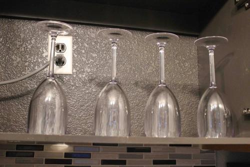 four wine glasses are lined up on a counter at Luxury Tempe Apt by ASU & Airport in Phoenix