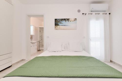 Un dormitorio blanco con una manta verde en una cama en Casa Marconi, en Matino