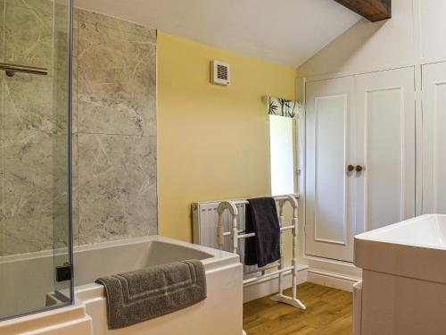 a bathroom with a bath tub and a sink at Ladycroft House in Hebden