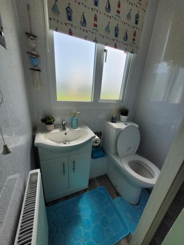 a bathroom with a toilet and a sink and a window at Casa B.R.I in Mablethorpe