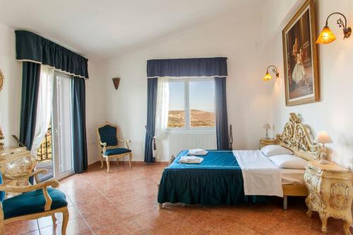 a bedroom with a bed and a chair and windows at Crete's Hidden Treasure - Dream Villa with Pool and Majestic Olive Tree Views in Skalánion