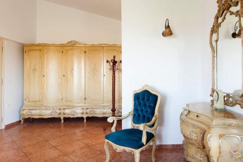 a room with a blue chair and a wooden cabinet at Crete's Hidden Treasure - Dream Villa with Pool and Majestic Olive Tree Views in Skalánion