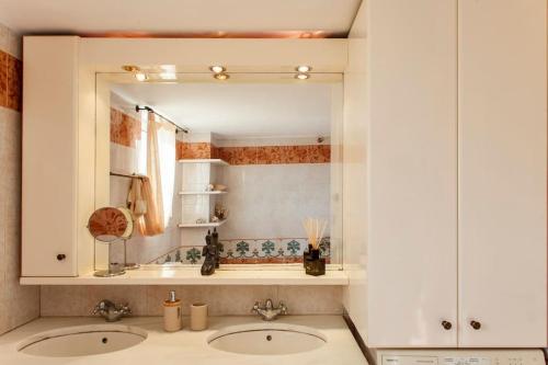 a bathroom with two sinks and a mirror at Crete's Hidden Treasure - Dream Villa with Pool and Majestic Olive Tree Views in Skalánion