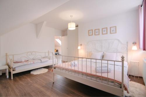 two beds in a bedroom with white walls and wood floors at Holiday house Daisy in Plaški