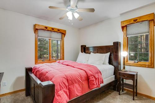 1 dormitorio con 1 cama con manta roja y 2 ventanas en Lakefront Bliss, en Rhinelander