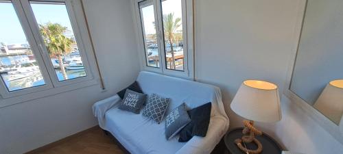 a living room with a blue couch and two windows at Port 3 in Tarragona