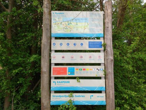 a sign in a forest with trees in the background at 't KISTJE Bed by the Sea in Koudekerke