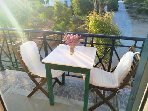 a table and two chairs on a balcony with a vase of flowers at Dolphin Rooms in Antiparos