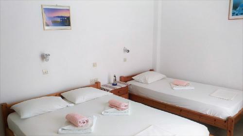 two beds in a room with pink pillows on them at Dolphin Rooms in Antiparos