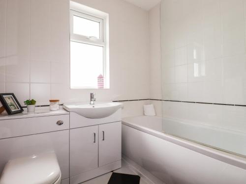 a white bathroom with a sink and a bath tub at Number 37 in Bude