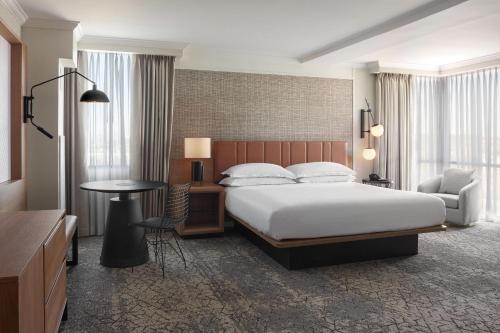 a hotel room with a bed and a chair and a table at Sheraton Parkway Toronto North Hotel & Suites in Richmond Hill