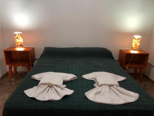 Una cama verde con toallas blancas encima. en Casas de Campo Famailla en Nono