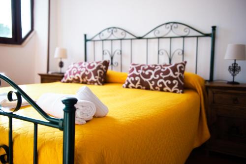 a bedroom with a bed with yellow sheets and pillows at Villa Conca Marco in Vanze