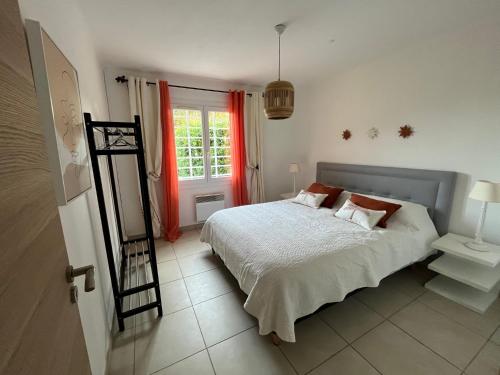 a bedroom with a bed and a window with red curtains at Maison à 400 M de la plage de Pampelonne in Saint-Tropez
