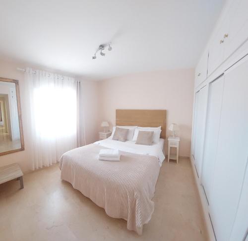 ein weißes Schlafzimmer mit einem weißen Bett und einem Fenster in der Unterkunft Luxurious Apartment 2 Bedroom 2 Bathroom Near Beach in Málaga