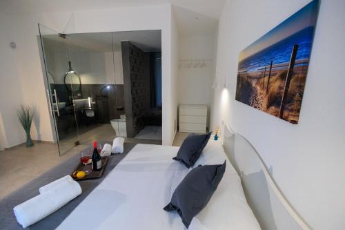 a bedroom with a white bed with a painting on the wall at Miramare rooms b&b in Avola
