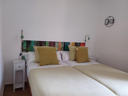 two beds in a room with white sheets and yellow pillows at LOFT de Tita Larrea in Arriondas