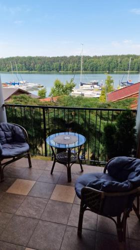 a patio with a table and chairs and a view of the water at Pokój na jezioro in Mikołajki