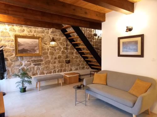 salon z kanapą i kamienną ścianą w obiekcie Romantic stone house by the sea **** w Kotorze
