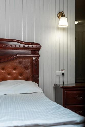 a bedroom with a bed with a wooden headboard and a lamp at Hotel Aristocrat in Chernivtsi