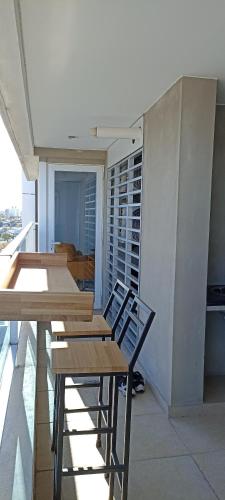 Zimmer mit Holztischen und -stühlen auf einem Balkon in der Unterkunft Diamantis Apartamento de Lujo y Confort in Montevideo