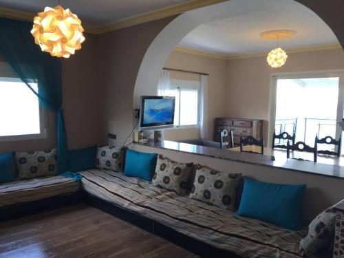 a living room with a couch and a tv at Villa Plage Ksar Sghir in Melîyech