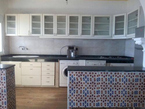 a kitchen with white cabinets and a dishwasher at Villa Plage Ksar Sghir in Melîyech