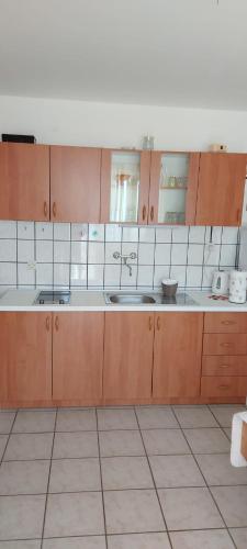 a large kitchen with wooden cabinets and white tile floors at Top Location in Živogošće