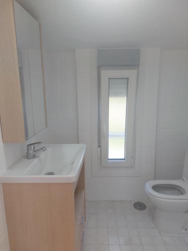 een witte badkamer met een wastafel en een toilet bij BertoaLand Relax y Diversión Apartamento de 2 dormitorios dobles con terraza privada y zona de juegos compartida in Carballo