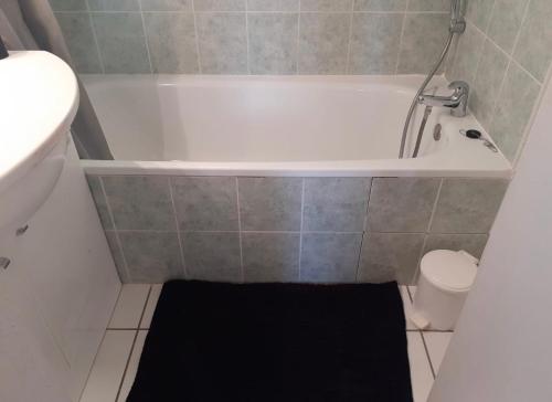 - une petite salle de bains avec une baignoire et un tapis noir dans l'établissement Belle Maisonette dans Residence 3* avec piscine partagée, à Saint-Saturnin-lès-Avignon