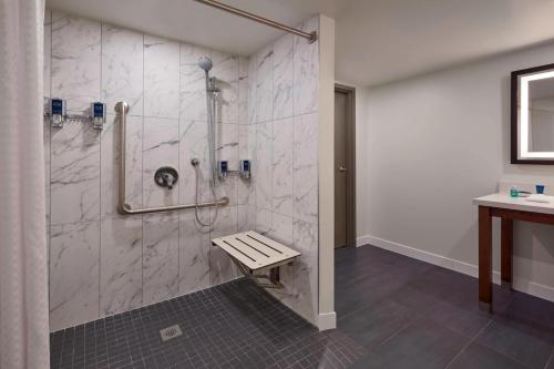a bathroom with a shower with a bench in it at Four Points by Sheraton Toronto Airport in Mississauga