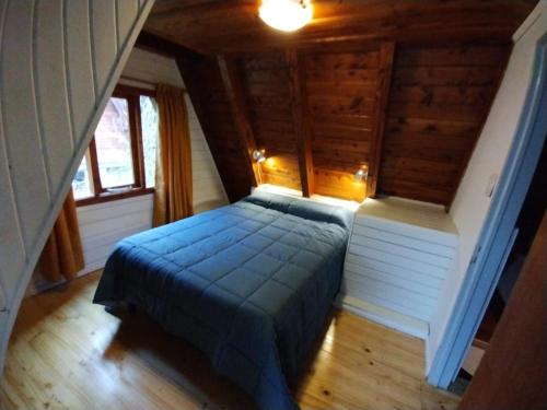 1 dormitorio con 1 cama en una casa de madera en Rayen hue en Esquel