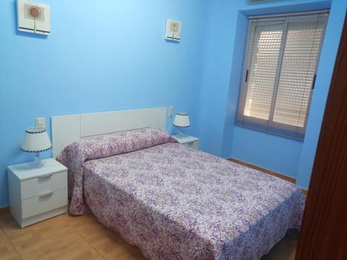 a blue bedroom with a bed and a window at Apartamento avenida in Elche de la Sierra