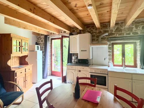 une cuisine avec une table en bois avec des chaises et un plateau de table dans l'établissement Gîtes de Rouvignac, à Avène