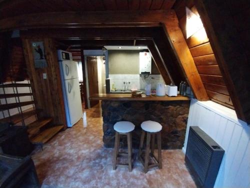 una cocina con 2 taburetes y una barra en una cabina en Rayen hue en Esquel