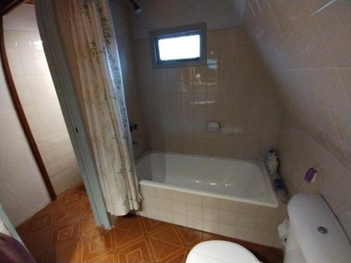 a bathroom with a tub and a toilet and a window at Rayen hue in Esquel