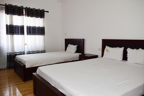 2 camas en una habitación de hotel con sábanas blancas en Holiday Villa, en Trincomalee