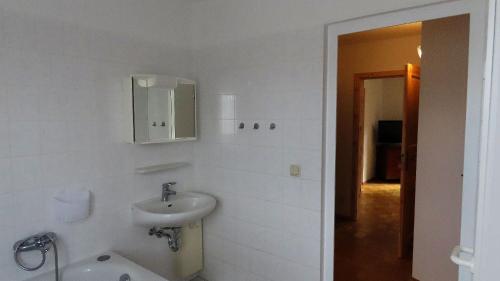 ein weißes Badezimmer mit einem Waschbecken und einem Spiegel in der Unterkunft Ferienwohnung "Specker Krug" in Kargow