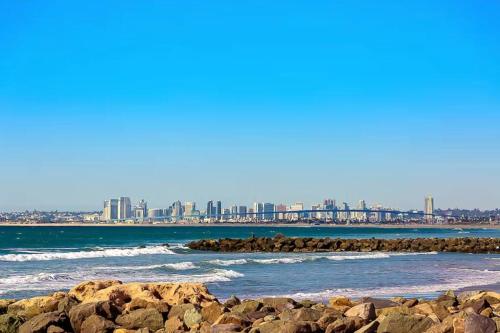 a beach with rocks and a city in the background at IB Seaside Paradise w/ Ocean Views! in Imperial Beach