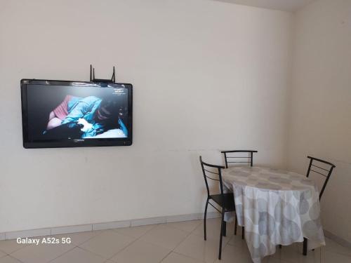 une télévision murale avec une table et des chaises dans l'établissement Begoniâ house, à Agadir