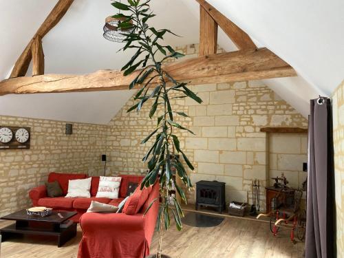 a living room with a red couch and a tree at Logis huit clos calme et romantique proche Saumur in Le Coudray-Macouard