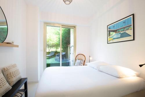 une chambre blanche avec un lit et une fenêtre dans l'établissement WE CANNES ! Exceptional 4 rooms apartment Cannes Center swimming pool, à Cannes