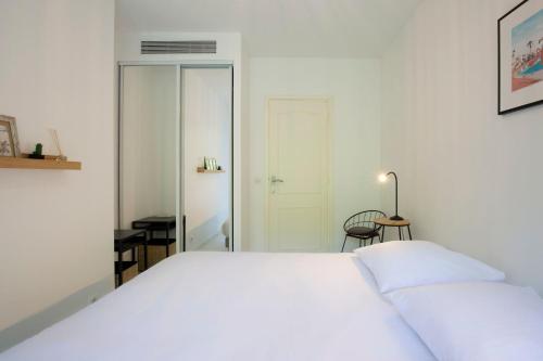 une chambre avec un grand lit blanc et un miroir dans l'établissement WE CANNES ! Exceptional 4 rooms apartment Cannes Center swimming pool, à Cannes